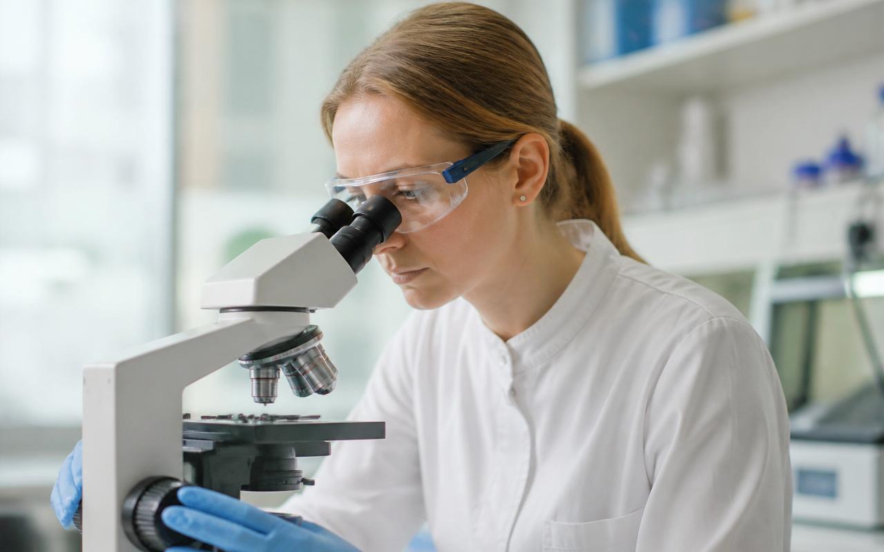 AIHA-accredited lab technician analyzing a mold sample on a microscope slide in a professional laboratory.