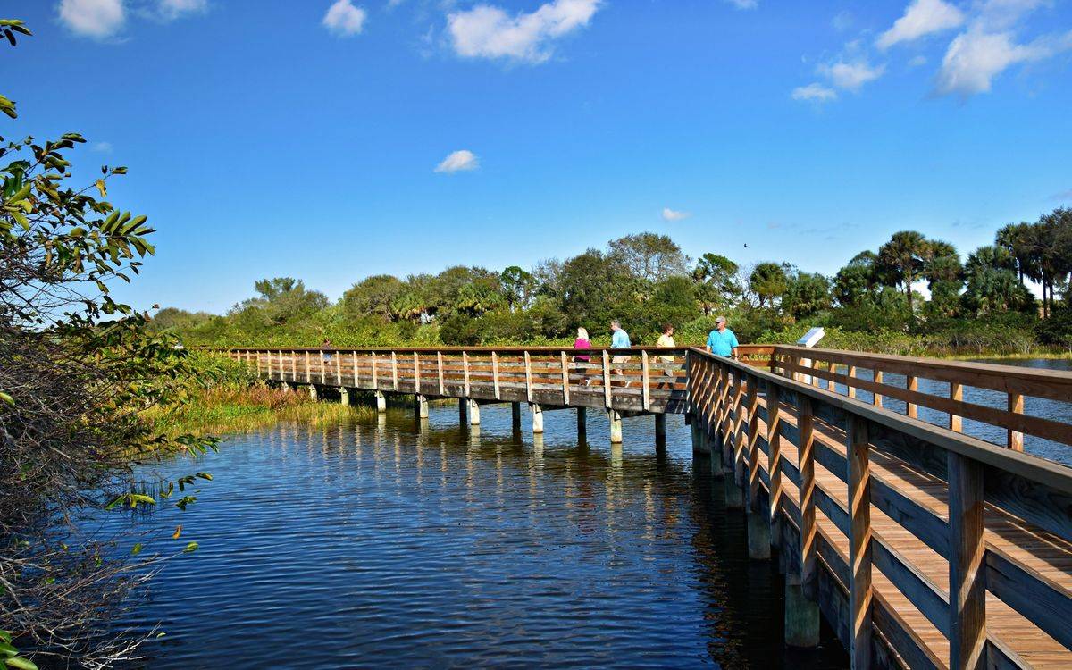 People walking a boardwalk bridge over water in Boynton Beach
