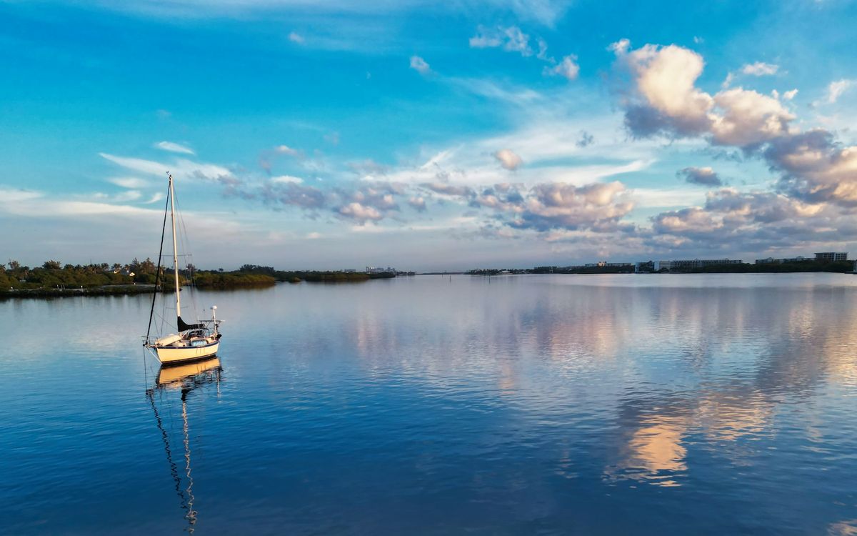 A sailboat at anchor on the Lake Worth Lagoon under evening cloud