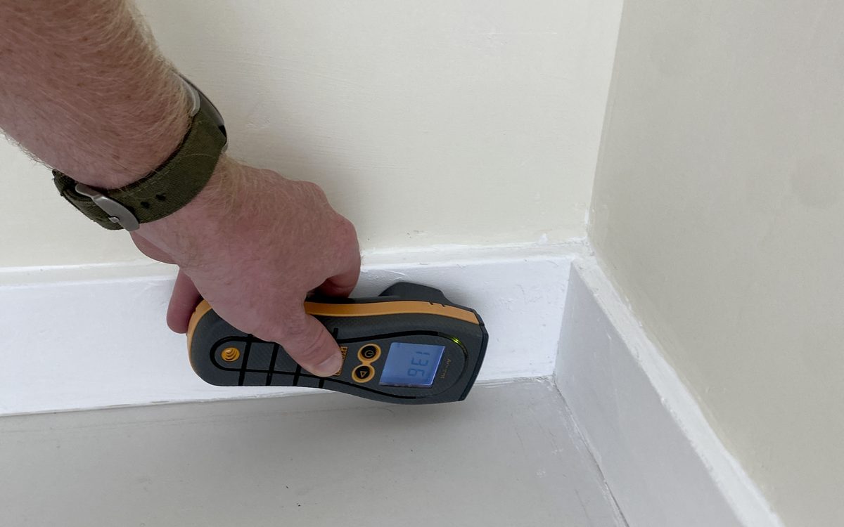 Mold inspection in Boynton Beach, FL: Moisture meter run along a baseboard during a mold inspection