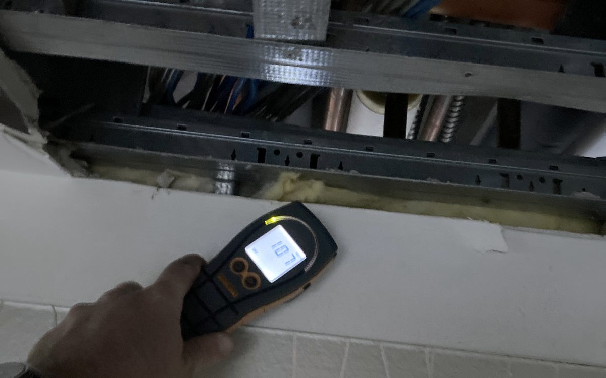 Mold inspection in Delray Beach, FL: Moisture meter used on a wall below an opened ceiling exposing ductwork