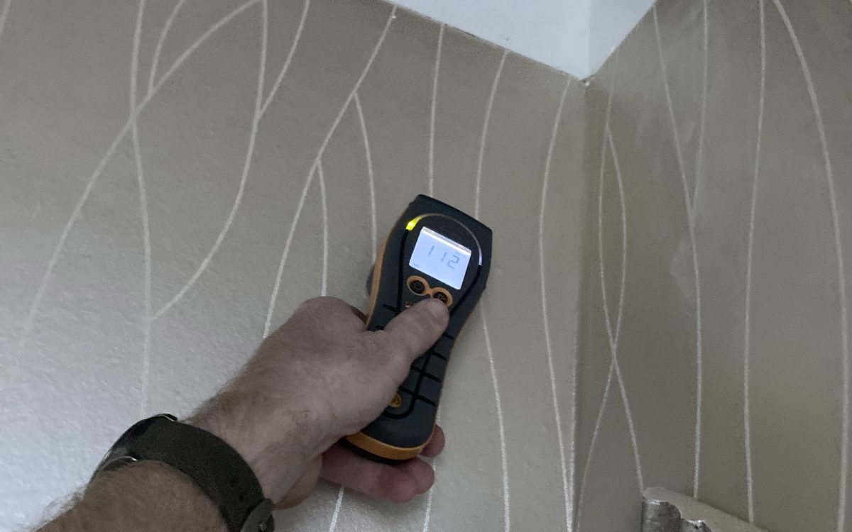 Mold inspection in Plantation, FL: Moisture meter held against patterned wallcovering during an inspection