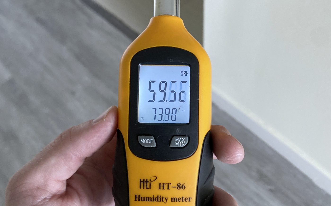 Digital hygrometer held in a hallway reading 59.6 percent relative humidity at 73.9 degrees Fahrenheit