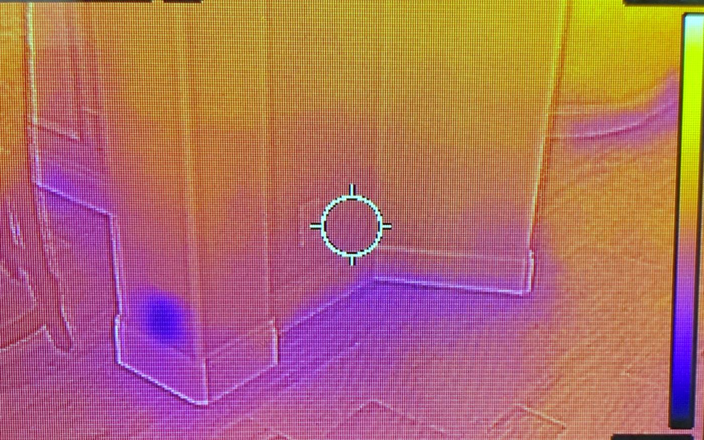 Infrared thermal image of a wall and floor junction showing a cooler area consistent with moisture