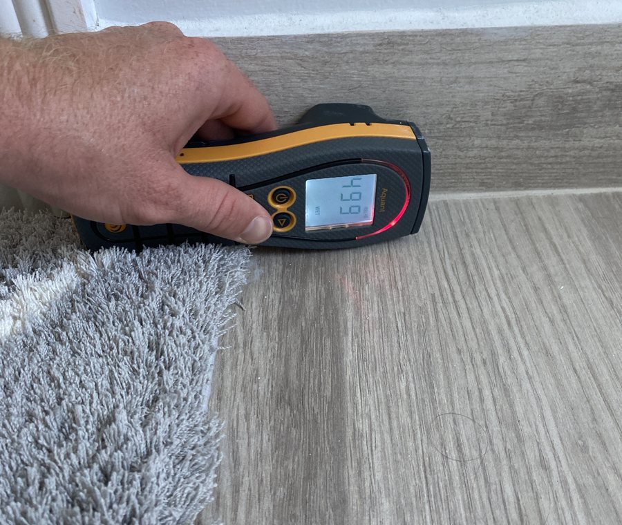 Safe Haven inspector taking an instrument reading on wall and baseboard material in a South Florida home.