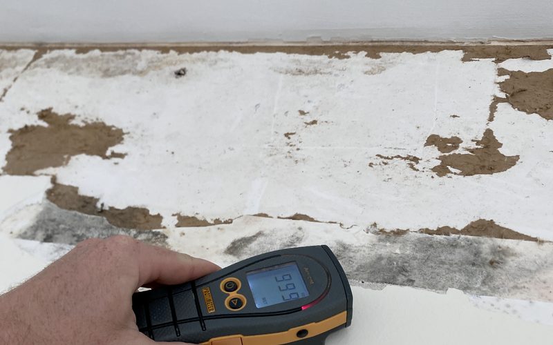 Infrared thermometer recording surface temperature on a damaged wall