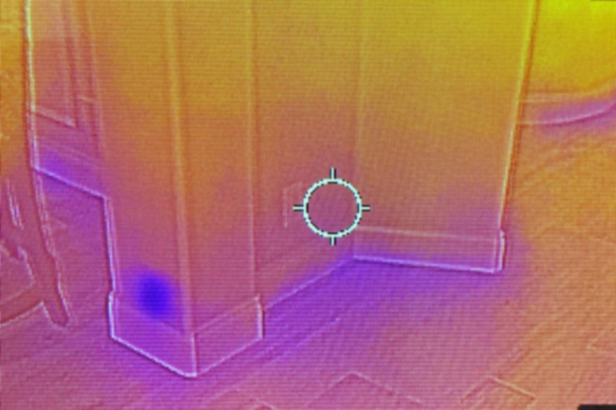 Infrared image of a wall and floor corner with a cooler area low on the wall
